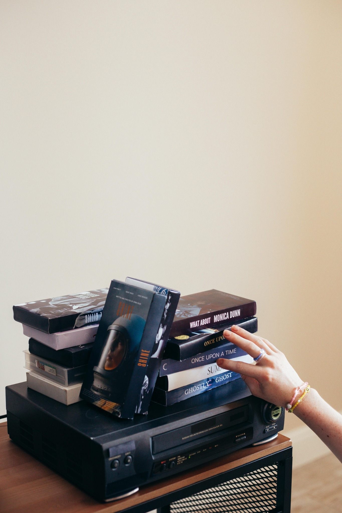 VCR with a stack of tape cases