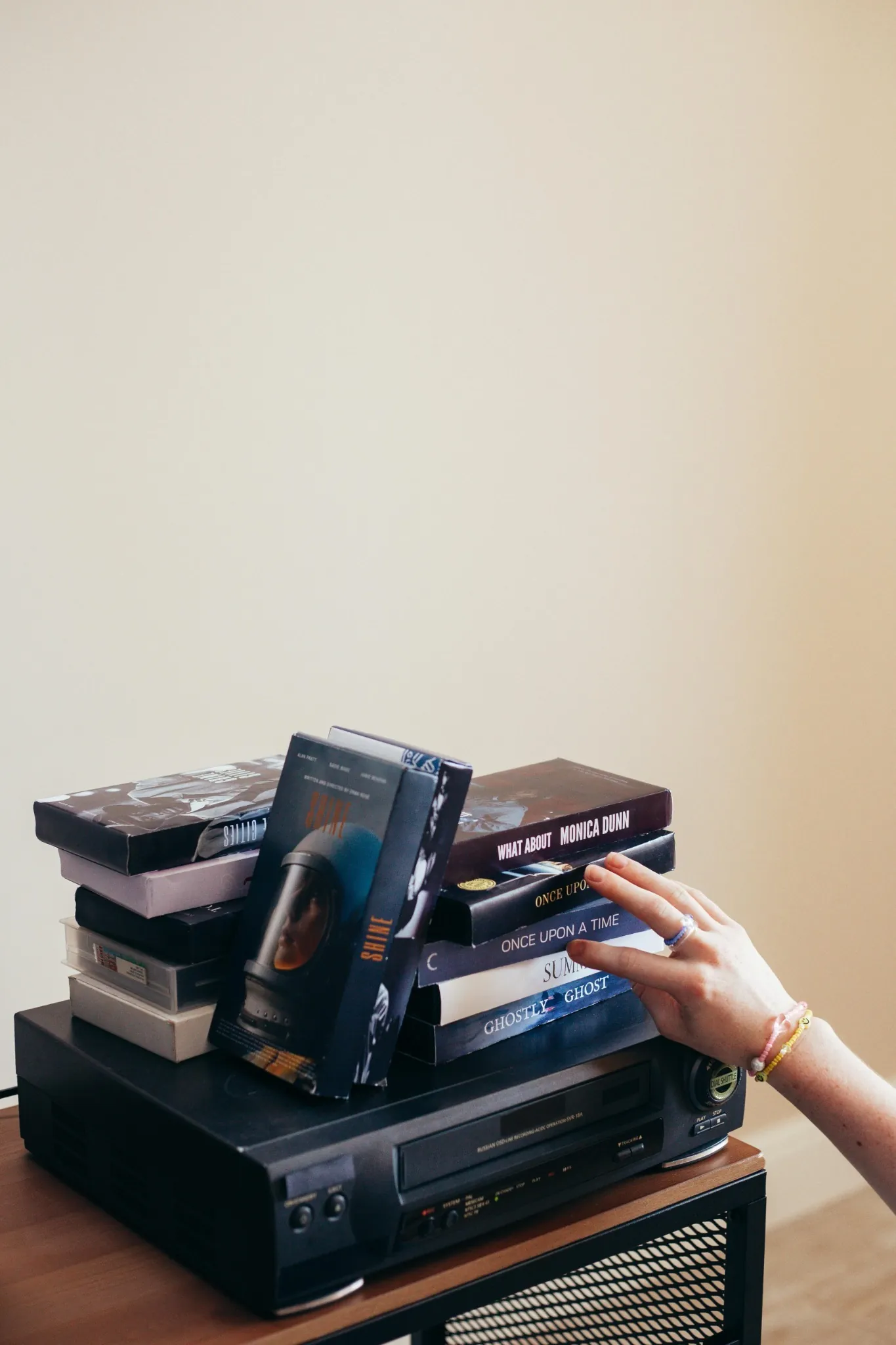 VCR with a stack of tape cases